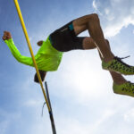 Germany, Man athlete jumping Hurdles on track